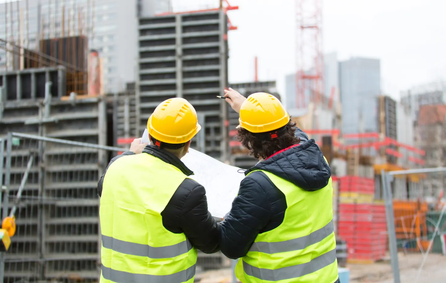Tecnici con i disegni di progetto davanti a un cantiere